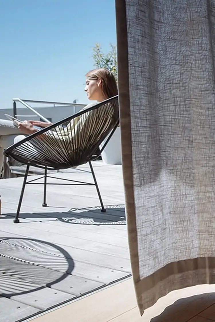 Sheer drapery opening onto a sunny balcony