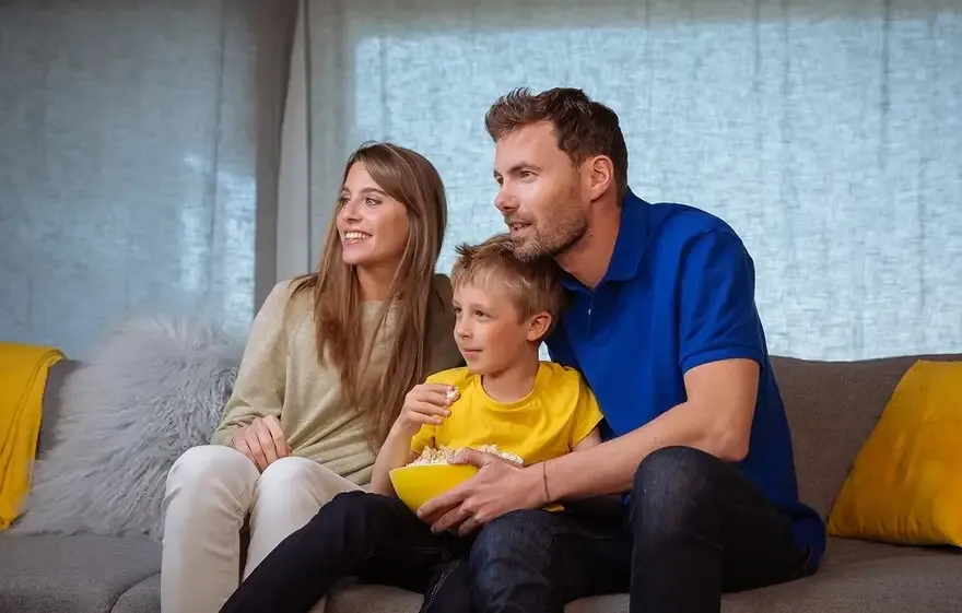 Family relaxing on a sofa in front of sheer drapery