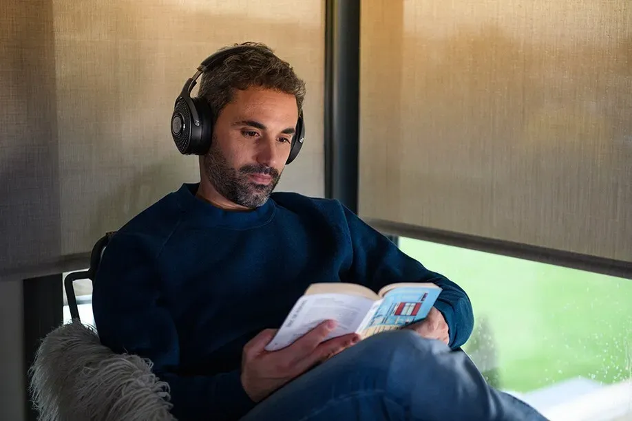 Man reading beside motorized roller shades lowered for glare control