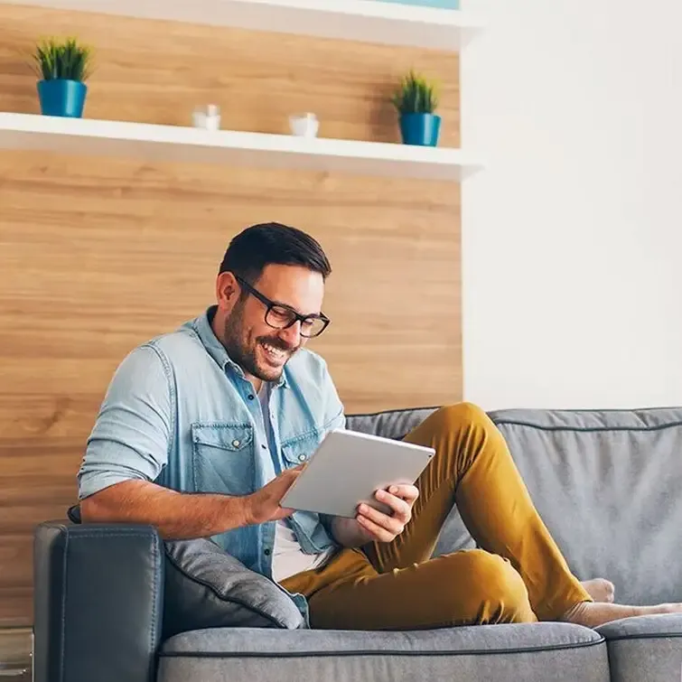 Man on his sofa controlling his home from a tablet